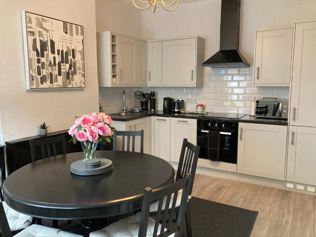 a kitchen with a table with a vase of flowers on it at Brampton Holiday Cottage @ 4 Gelt Road in Brampton