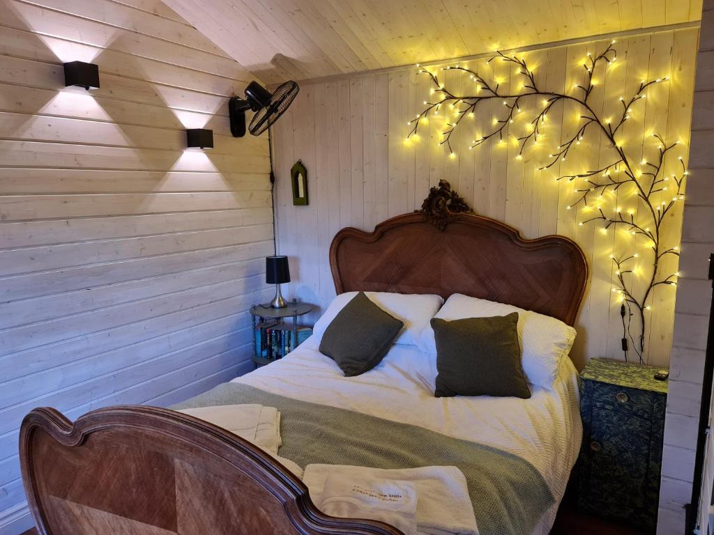 a bedroom with a bed with lights on the wall at The Malvern Hills Courtyard Cabins. (Barbara Cabin) in Great Malvern