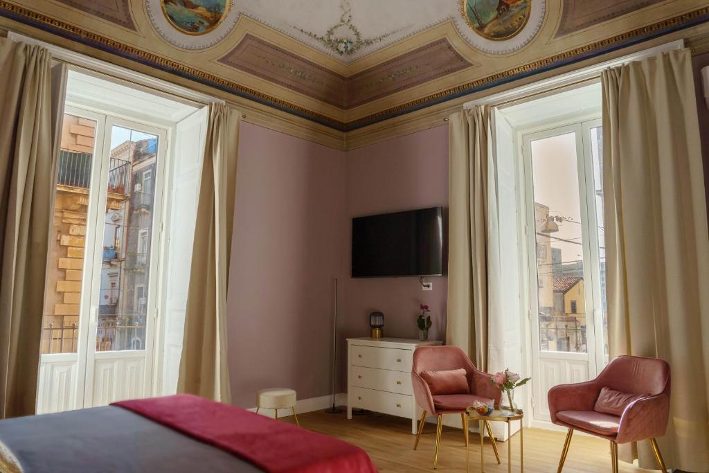 1 Schlafzimmer mit einem Bett und 2 Stühlen sowie einem TV in der Unterkunft Le Volte And Suite in Catania