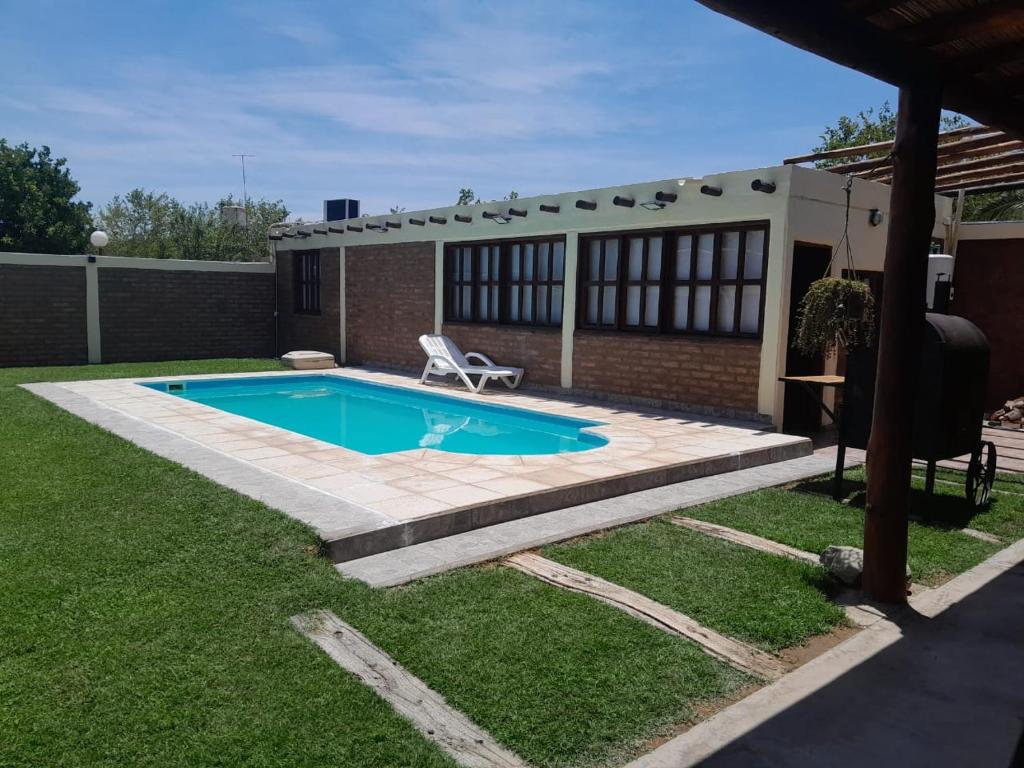 a swimming pool with a chair in a yard at Hermosa casita con quincho y amplia pileta TODAS LAS COMODIDADES Paz total in Ullún