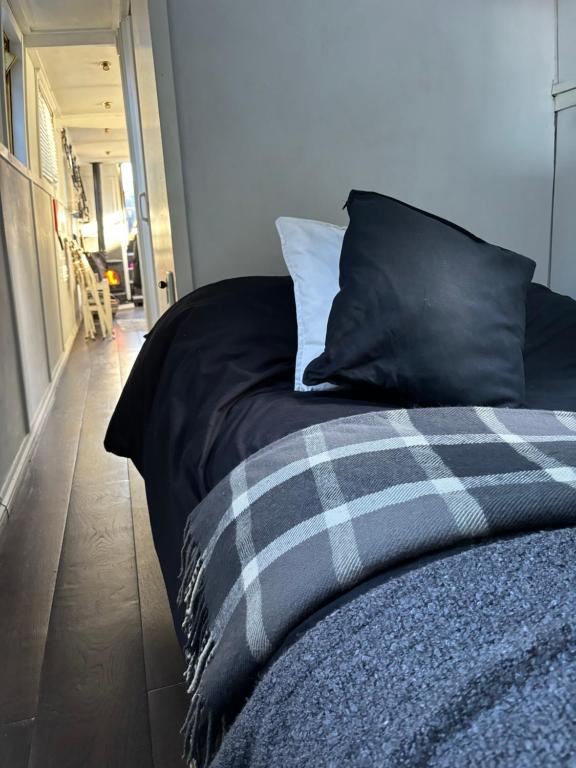 a bed with a black comforter and a pillow at Narrow Boat moored in London in London