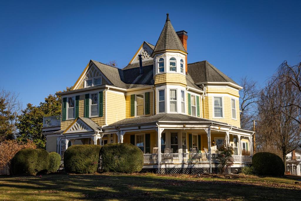 a large yellow house with a tower on top at The Oaks Victorian Inn in Christiansburg