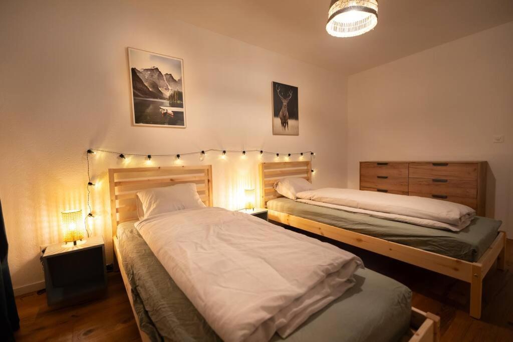 two beds in a bedroom with lights on the wall at Appartement spacieux au centre de la Gruyère in Broc