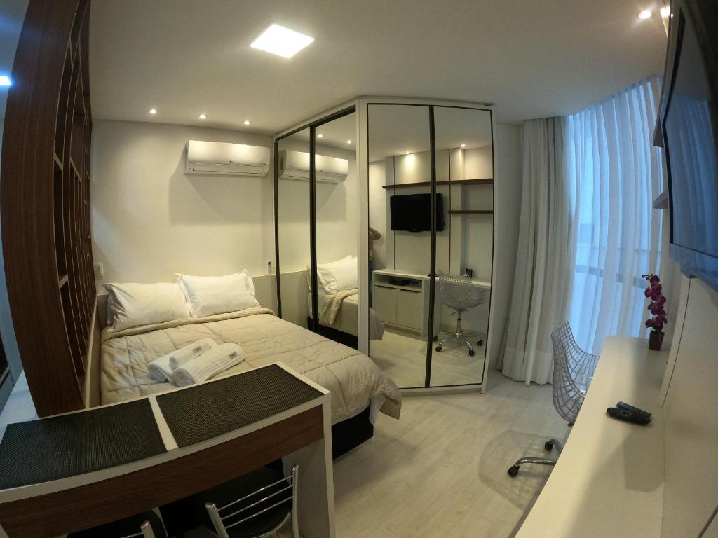 ein Hotelzimmer mit einem Bett und einem Spiegel in der Unterkunft Studio novíssimo e aconchegante no Juvevê. in Curitiba