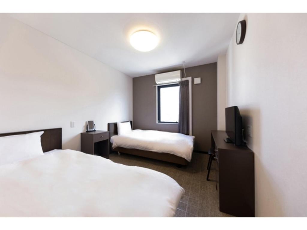 大阪市にあるOKINI HOTEL namba - Vacation STAY 40741vのベッド2台とテレビが備わるホテルルームです。