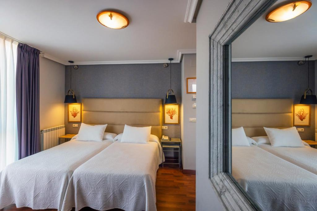 twee bedden in een kamer met een spiegel bij Hotel Verdemar in Ribadesella