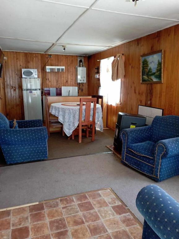 uma sala de estar com cadeiras azuis e uma mesa em Cabañas Ancud Magico em Ancud