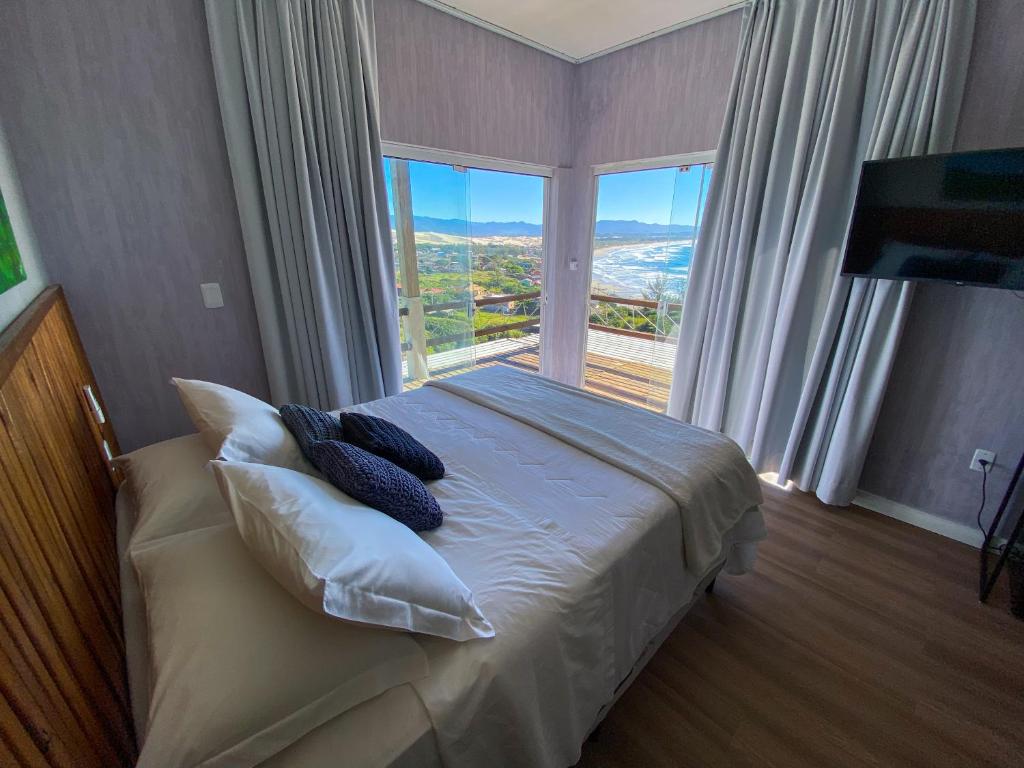 a bedroom with a bed with pillows and a large window at Pousada PARAÍSO 26 in Imbituba