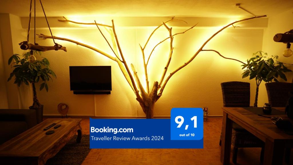 ein Wohnzimmer mit einem Fake-Baum an der Wand in der Unterkunft Holzmichel FEWO mit Balkon in Cottbus