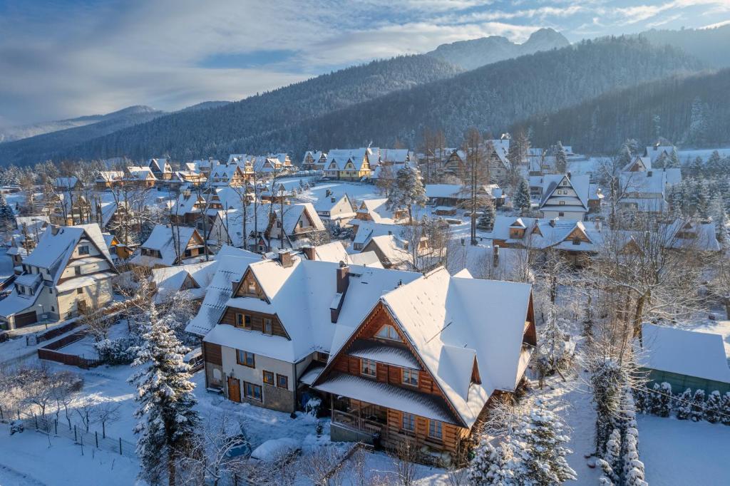 un pueblo cubierto de nieve con montañas en el fondo en Willa Skorusa, en Zakopane