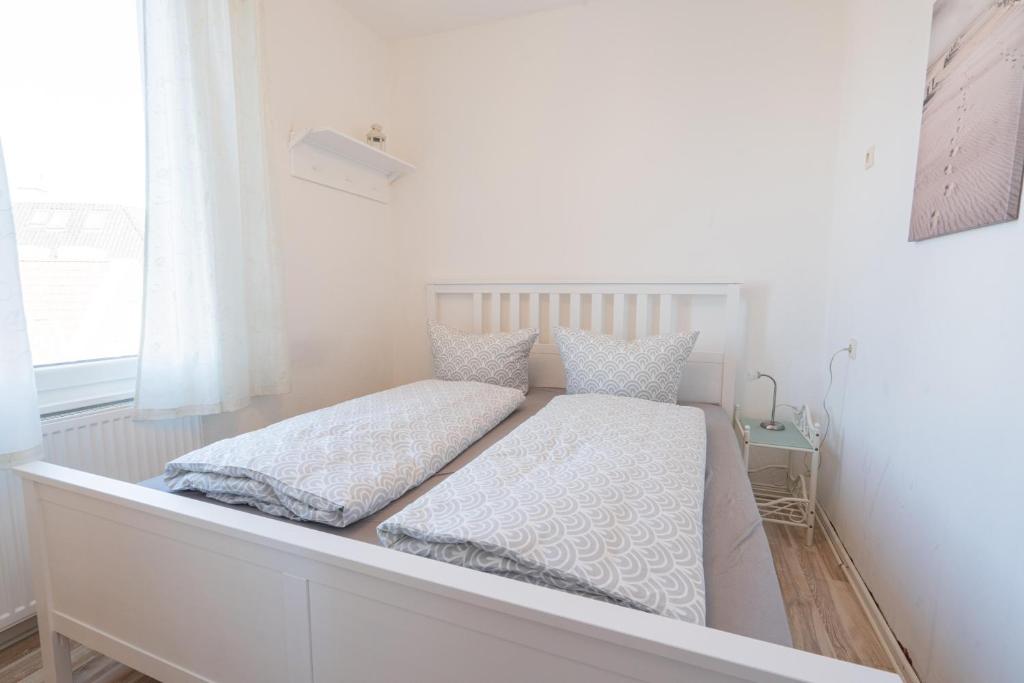 a white bed with two pillows on top of it at Strandhafer in Norderney