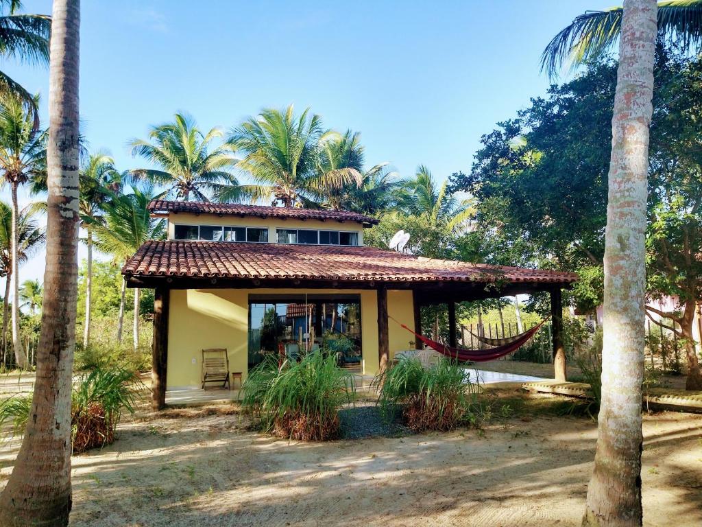 a house with a hammock in front of palm trees at Ampla casa em condomínio à beira d' agua in Caravellas