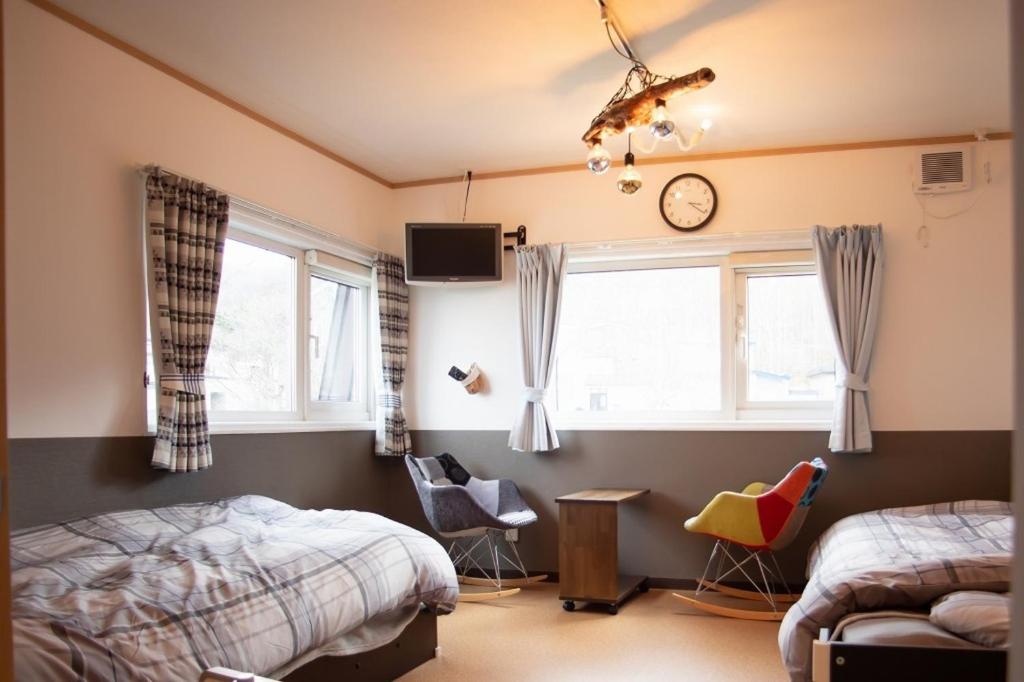 a bedroom with two beds and a clock on the wall at Otaro Village - Vacation STAY 63281v in Otaru