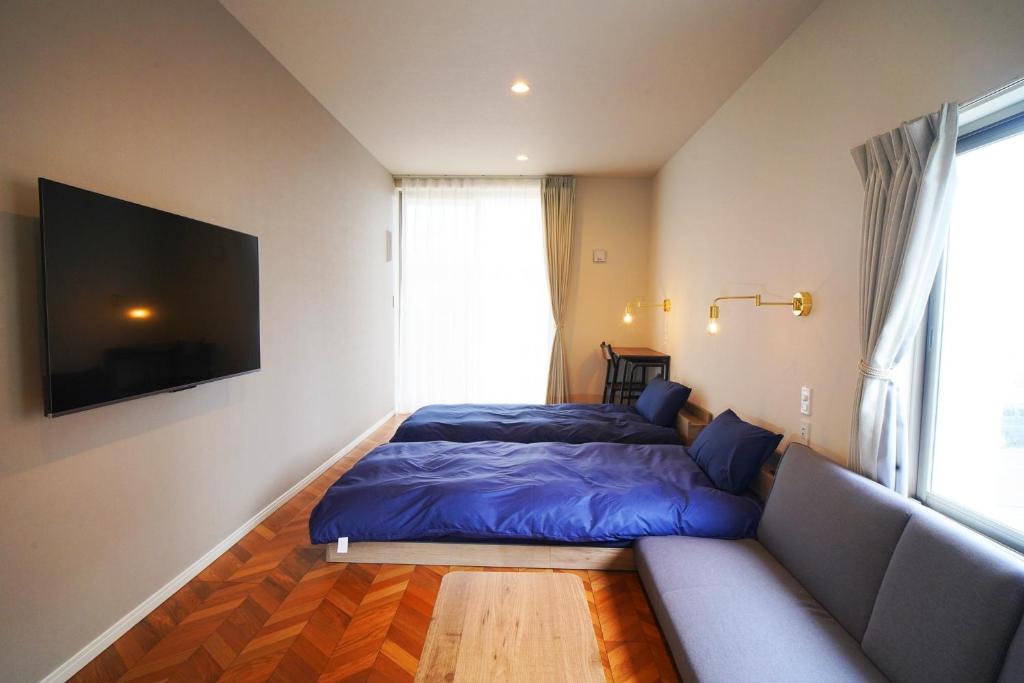 ein Schlafzimmer mit einem Bett, einem Sofa und einem TV in der Unterkunft Etcetera Niijima Nagisa Building - Vacation STAY 02083v in Niijimamura