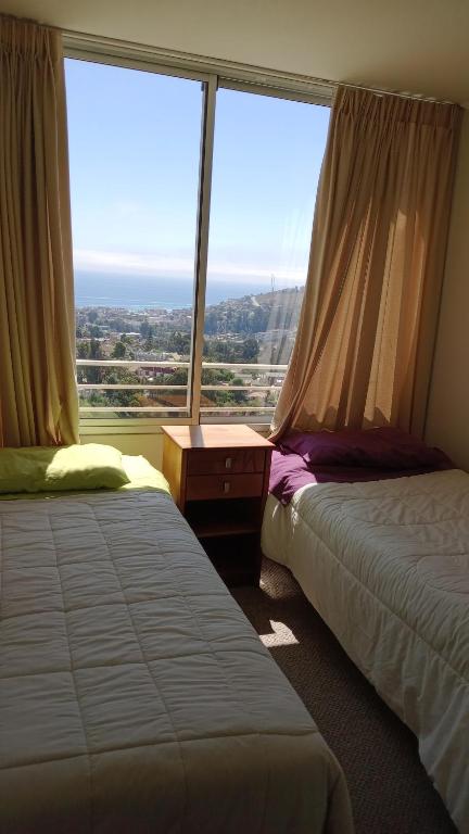 two beds in a room with a large window at Habitación Costa Reñaca in Viña del Mar