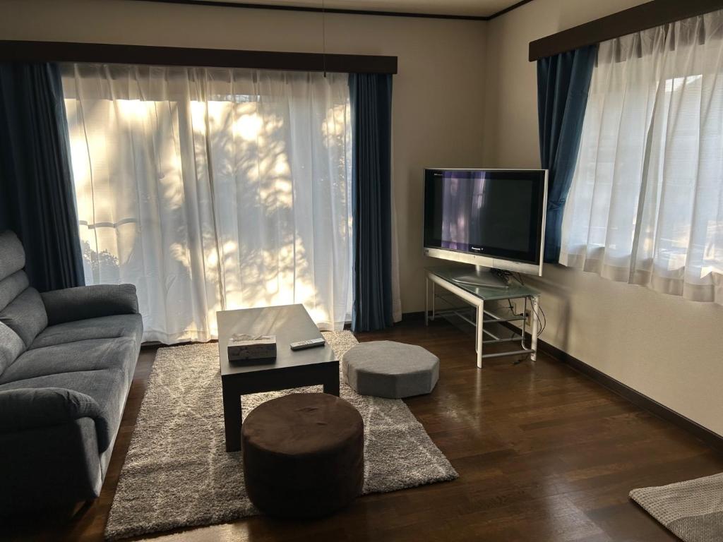 uma sala de estar com um sofá e uma televisão de ecrã plano em Guest House Fuji no Yado Akebono Building A - Vacation STAY 74316v em Fujiyoshida