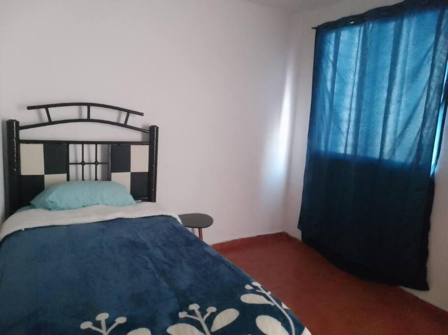 a bedroom with a bed with a blue blanket and blue curtains at duplicado in Tlacote el Bajo