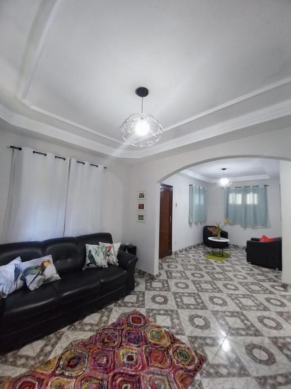 a living room with a black couch and a rug at Casa ampla com Wi-Fi e garagem para dois veículos in Campos dos Goytacazes