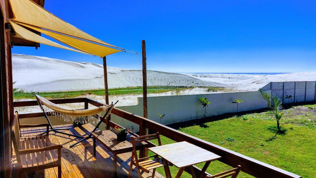 um alpendre com uma rede de descanso, uma mesa e cadeiras em Cabana das Dunas beira mar em Jaguaruna