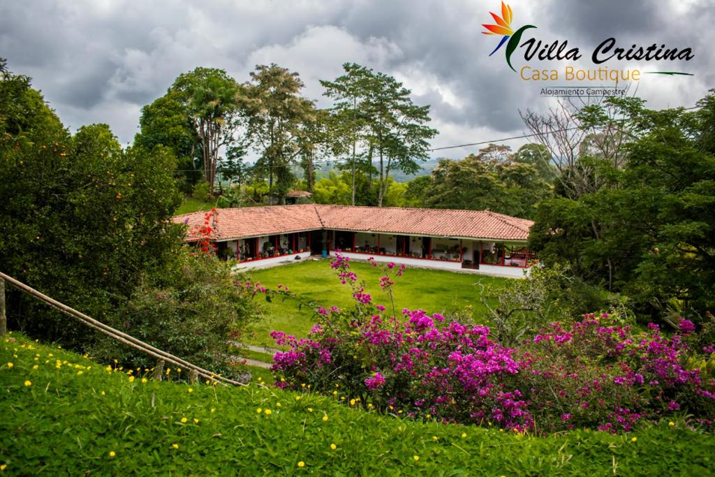 a house in the middle of a field with flowers at Villa Cristina - Casa Boutique in Pereira
