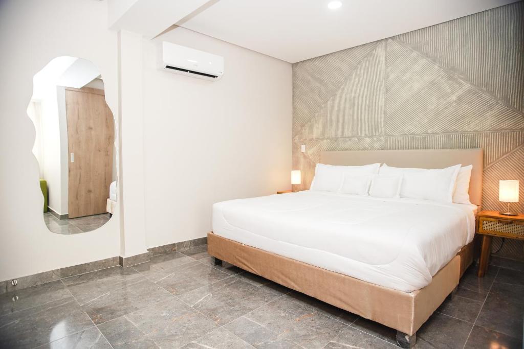 1 dormitorio con 1 cama blanca grande y espejo en Bahía Boutique House, en Cartagena de Indias