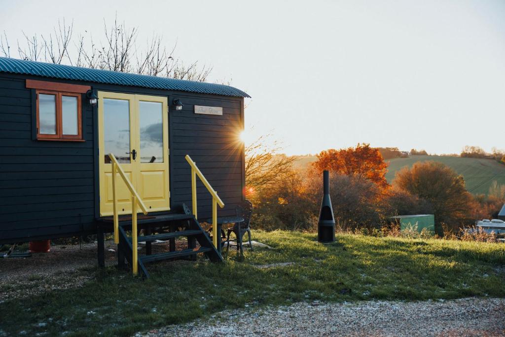 una casa pequeña con una puerta amarilla y un tobogán en The Hive Shepherds hut en Offton