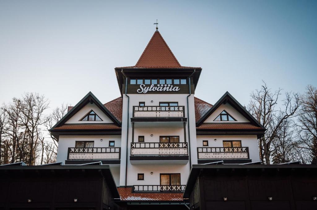 ein großes weißes Gebäude mit einem Dach in der Unterkunft Pensiunea Sylvania in Sovata