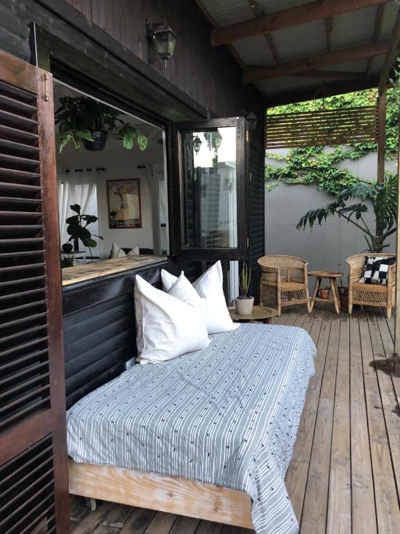 a bed on a wooden deck with a window at Urban Plett in Plettenberg Bay