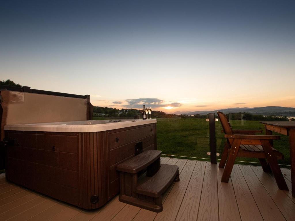 a hot tub on a deck with a chair and a table at 1 bed in Langbank 73845 in Langbank