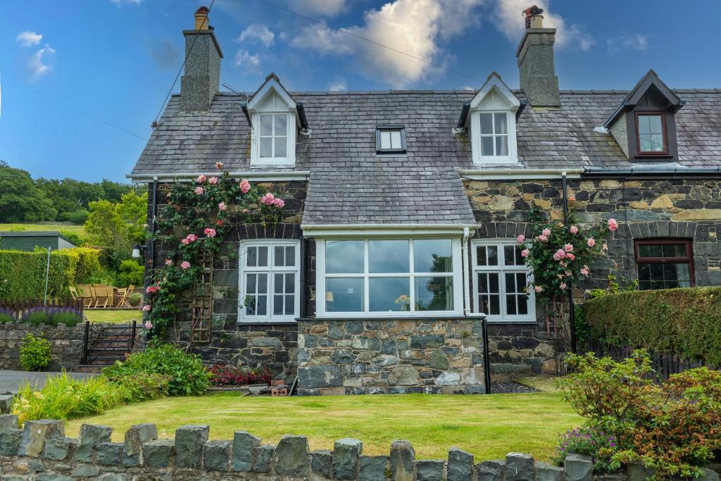 an old stone house with a large window at Uwch-Y-Mor in Llanfairfechan