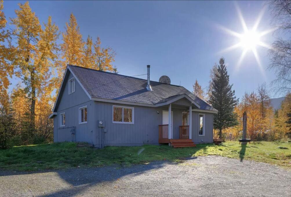 uma pequena casa azul com o sol ao fundo em Cozy Cottage w/Pioneer Peak View em Palmer