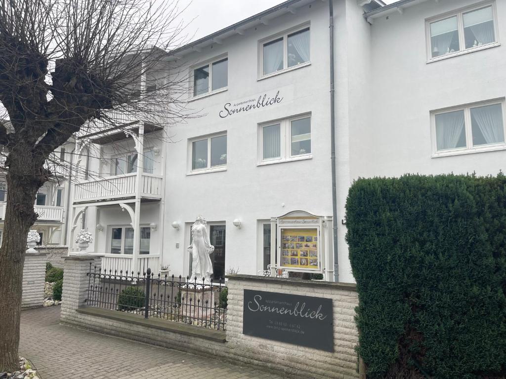 a white building with a statue in front of it at Apartmenthaus Sonnenblick in Binz