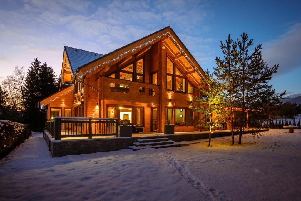 ein großes Holzhaus mit Schnee auf dem Boden in der Unterkunft Pillow House Montibus in Pribylina
