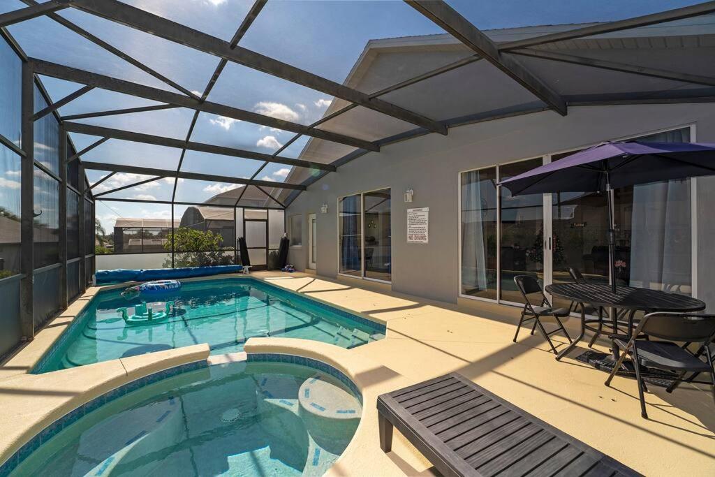 een zwembad met een tafel en stoelen en een parasol bij Poolside Orlando Oasis in Orlando