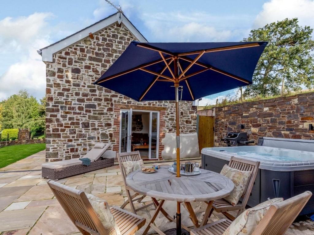 a patio with a table with an umbrella and a hot tub at 2 Bed in Bishops Tawton 79393 in Bishops Tawton