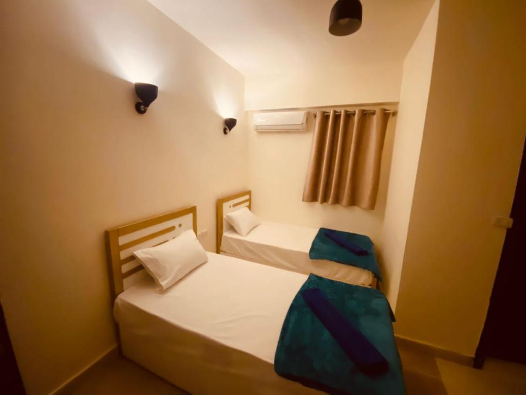 Brother Hotel Dahab في دهب: سريرين في غرفة صغيرة مع أضواء على الحائط