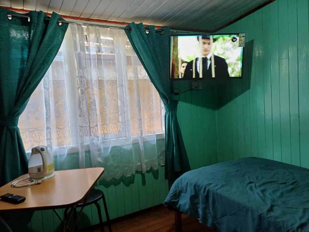 uma televisão num quarto com uma cama e uma mesa em Habitación cómoda por día em Valdivia