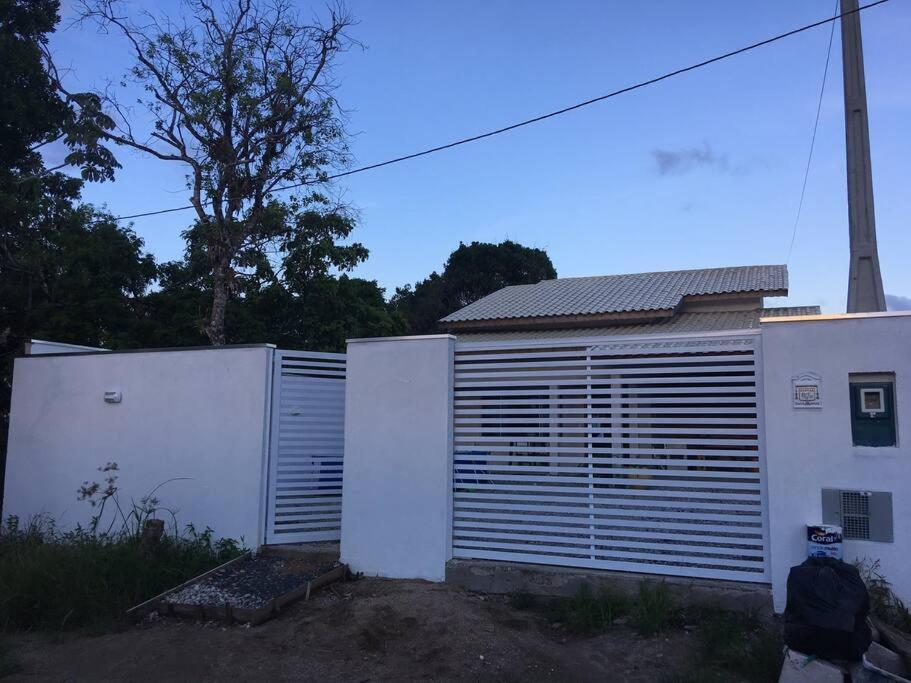 a white fence next to a white building at Casa de Praia in Cananéia