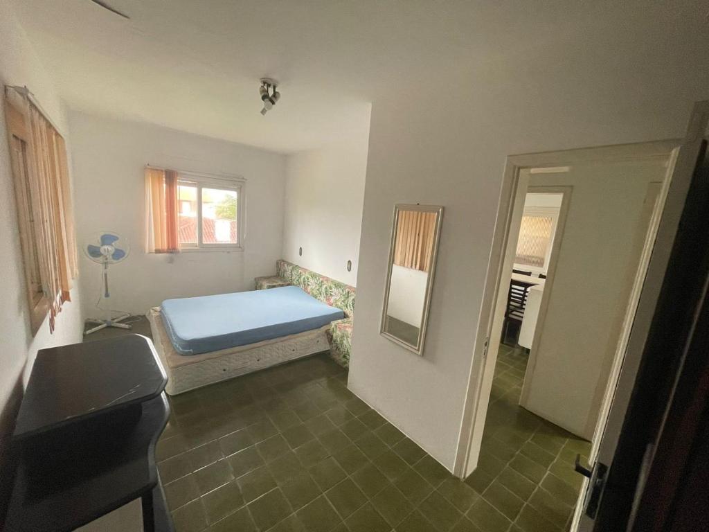 a bedroom with a bed and a window and a mirror at Residencial Brilha Mar in Capão da Canoa