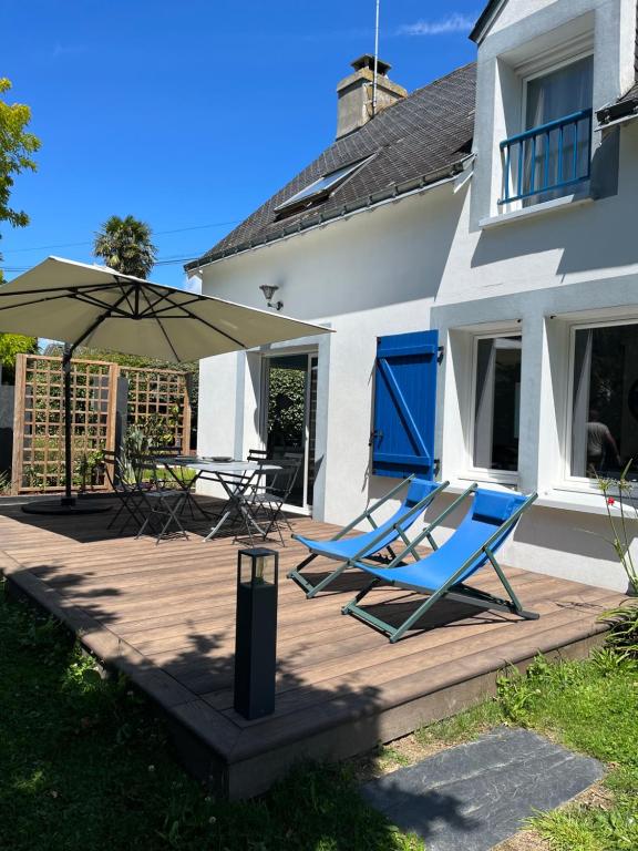 two blue chairs and an umbrella on a wooden deck at Maison Hoëdic in La Trinité-sur-Mer