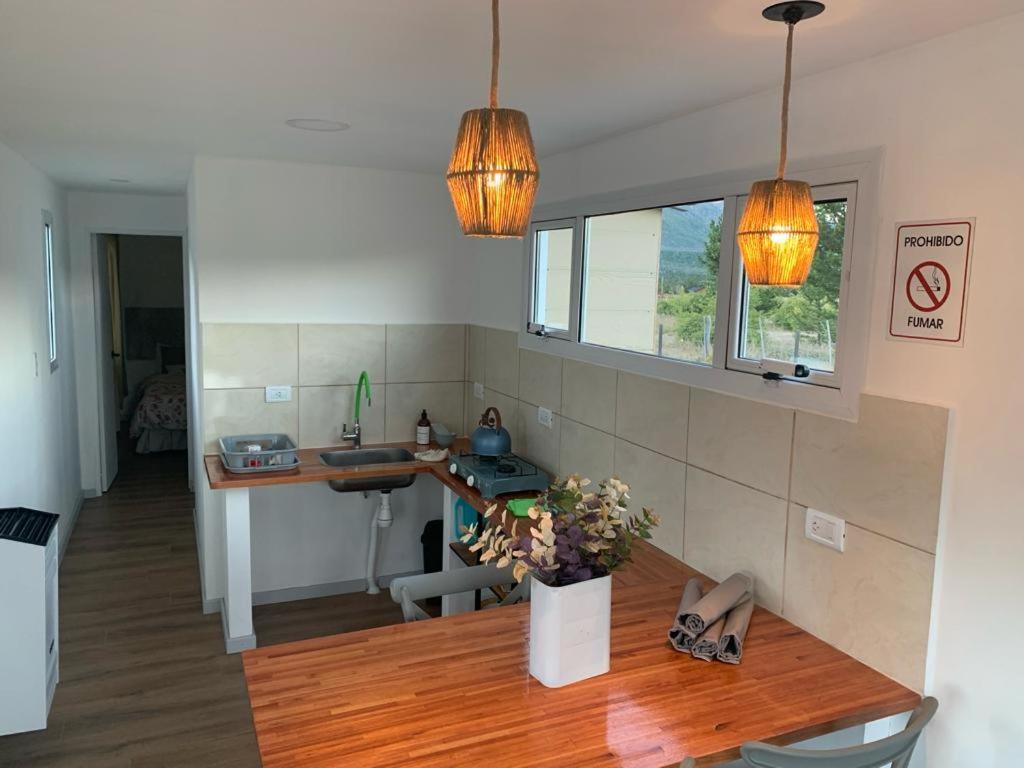 a kitchen with a table and a sink and two lights at La Carmela Container house's in Esquel