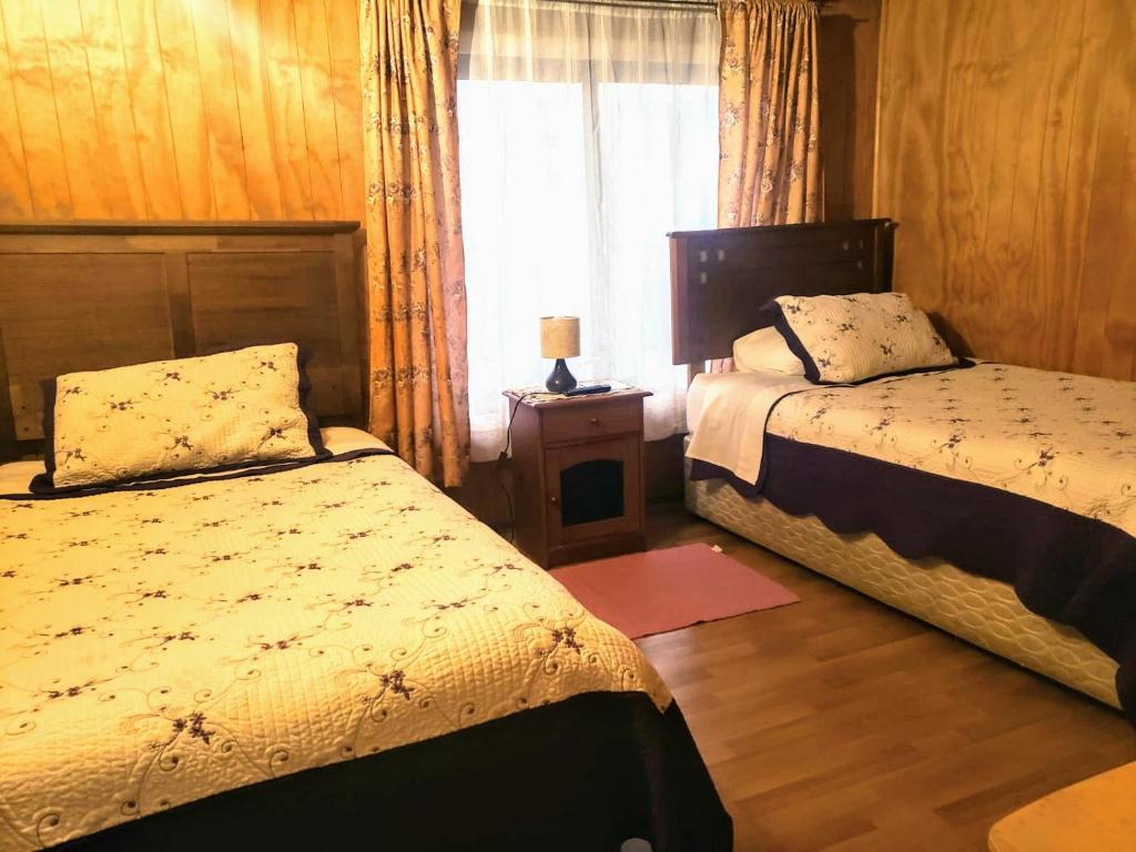 a bedroom with two beds and a window at HOSTAL AIRE PATAGON in Coihaique