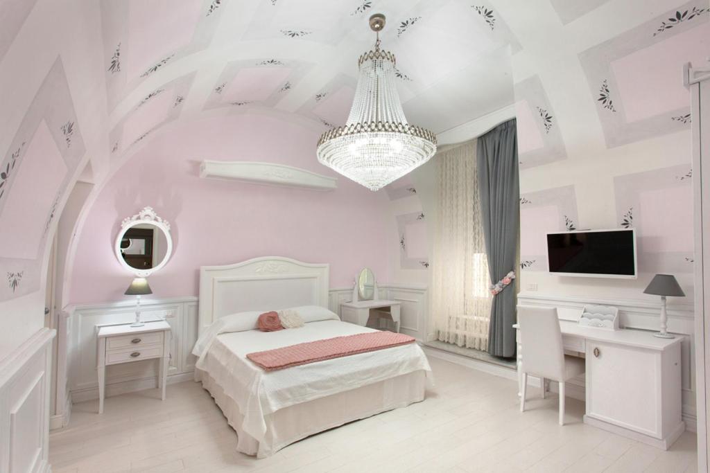 a white bedroom with a bed and a desk and a tv at Domus Rosa in Naples