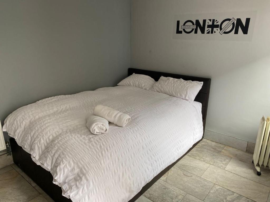 a white bed with two rolled towels on it at Luxurious En-suite Soft Water Air Conditioning TV RIPPLE in London