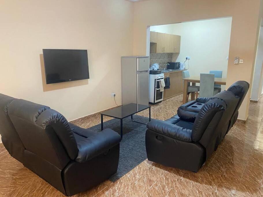 a living room with two leather couches and a television at Izzy Guest House in Brikama