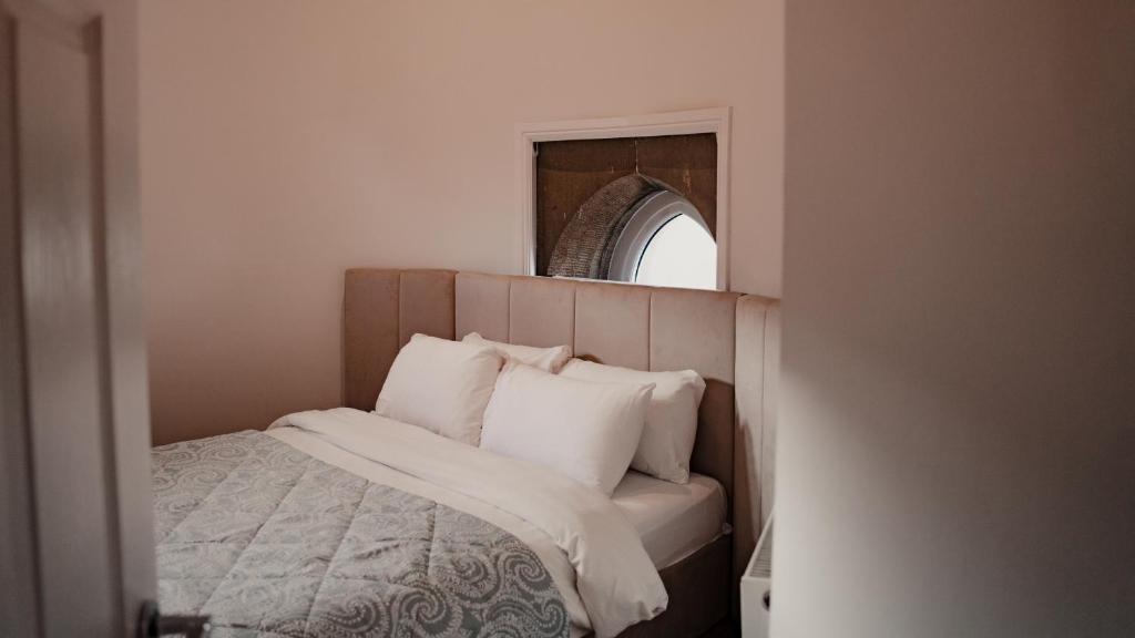 um quarto com uma cama com almofadas brancas e um espelho em Royal Chambers Serviced Apartments em Glasgow