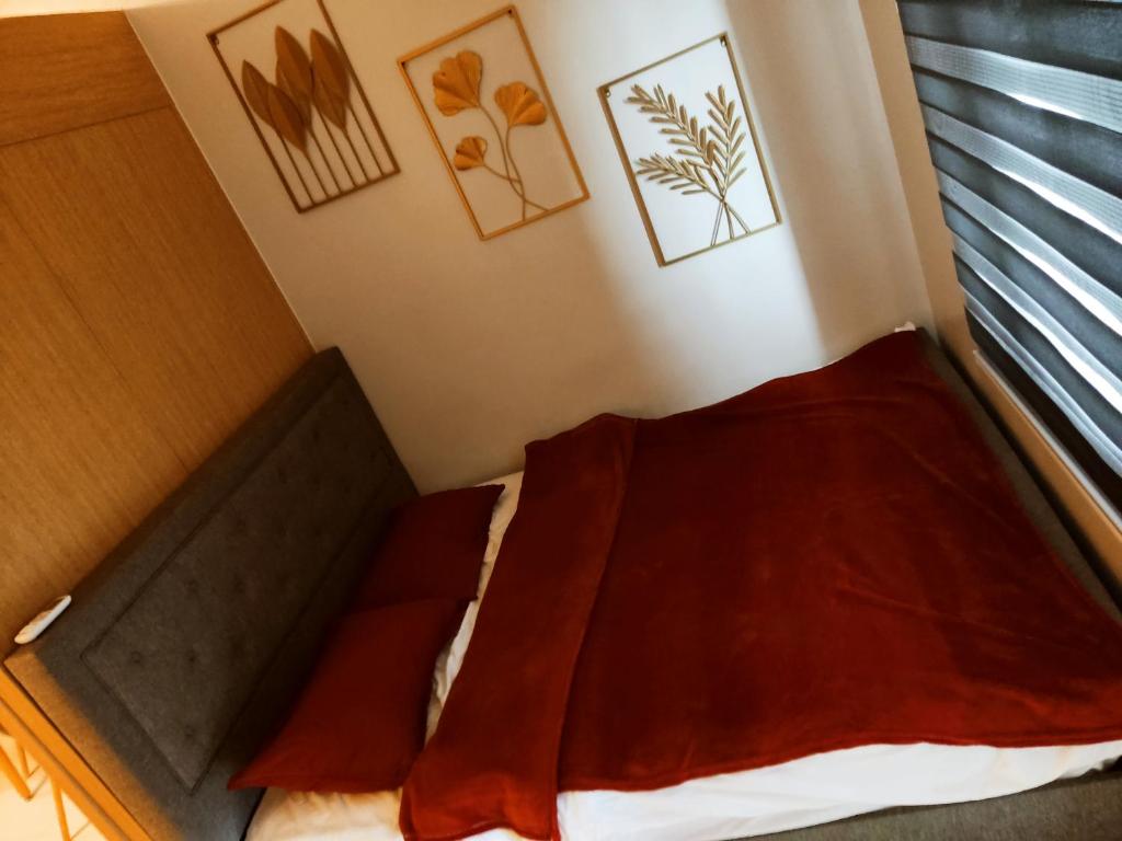 マニラにあるThe Grass Residencesの小さなベッドルーム(赤いシーツと窓付きのベッド付)