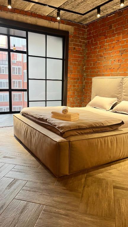 een groot bed in een kamer met een bakstenen muur bij Люкс в стиле LOFT in Pavlodar