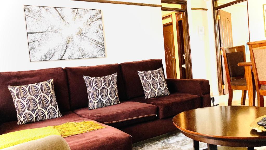 a living room with a brown couch and a table at Gem in Busia