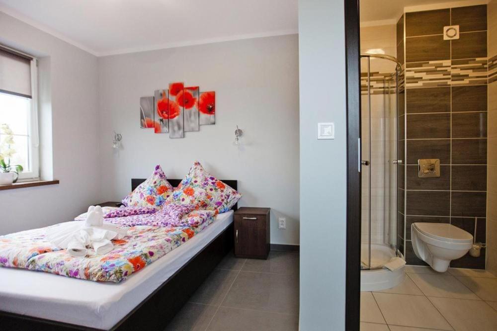 a bedroom with a bed and a bathroom with a shower at Comfortable premium class apartment shared swimming pool Gaski in Gąski